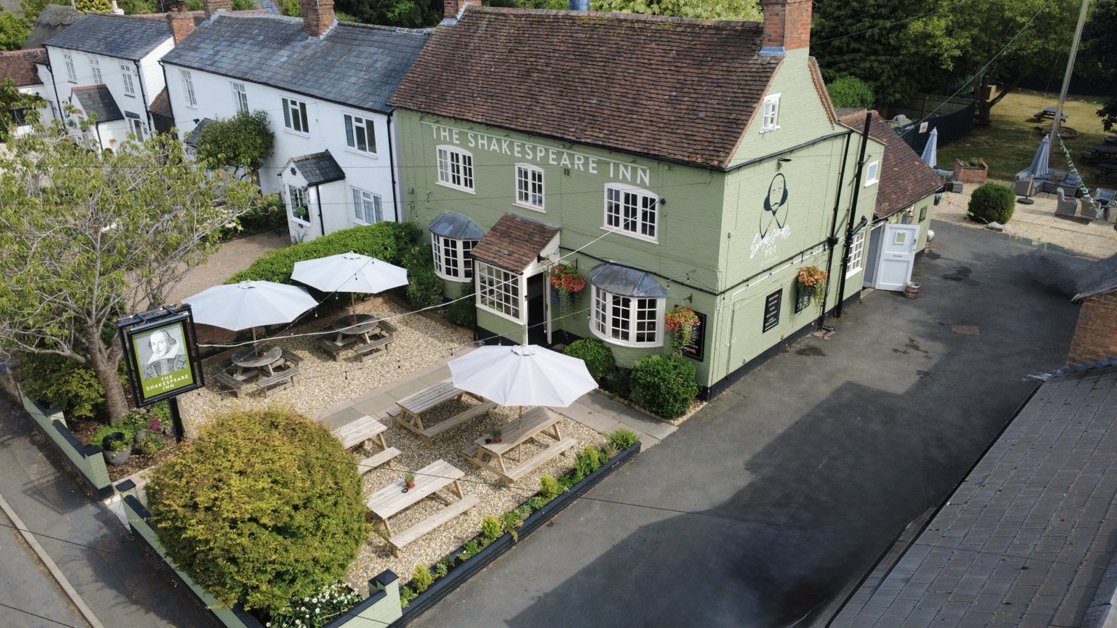 Aerial view of The Shakespeare Inn and its front garden set up with parasols and benches.